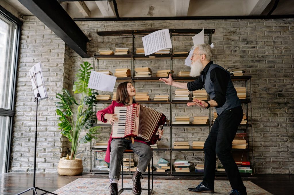Elderly man teaching teenager to play accordion, showcasing flying music sheets in a cozy home setting.
