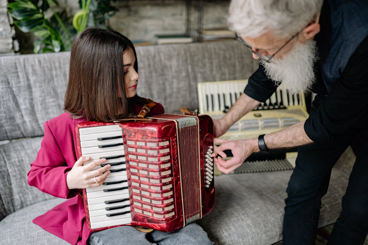 A child playing an accordion under the guidance of a teacher indoors.